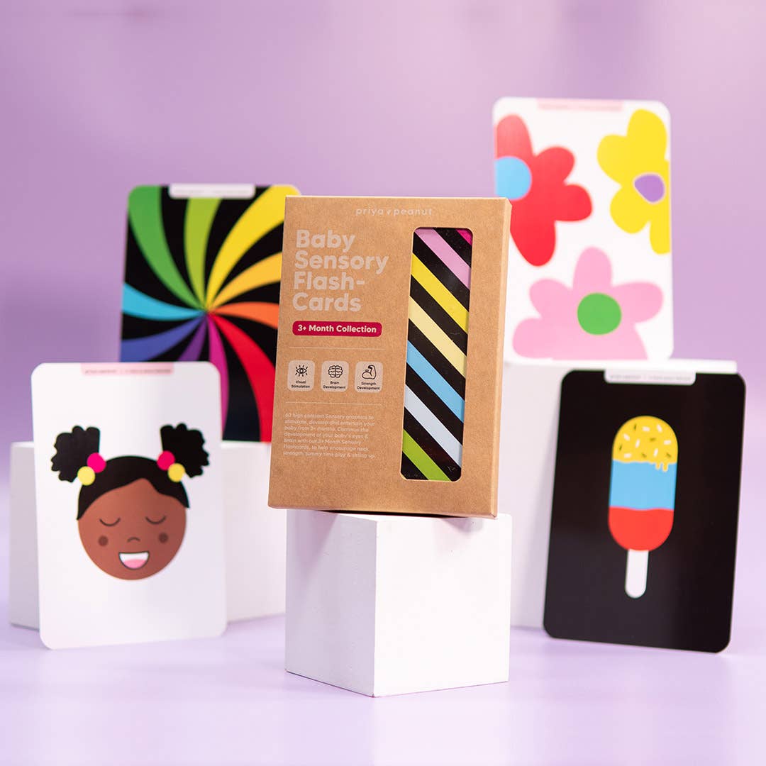 Priya & Peanut's Colour Sensory Flash Cards For Babies (3+ Months) - Sensory Toy are displayed on white stands against a purple background, showing abstract patterns, flowers, a smiling face, and a popsicle for baby development.