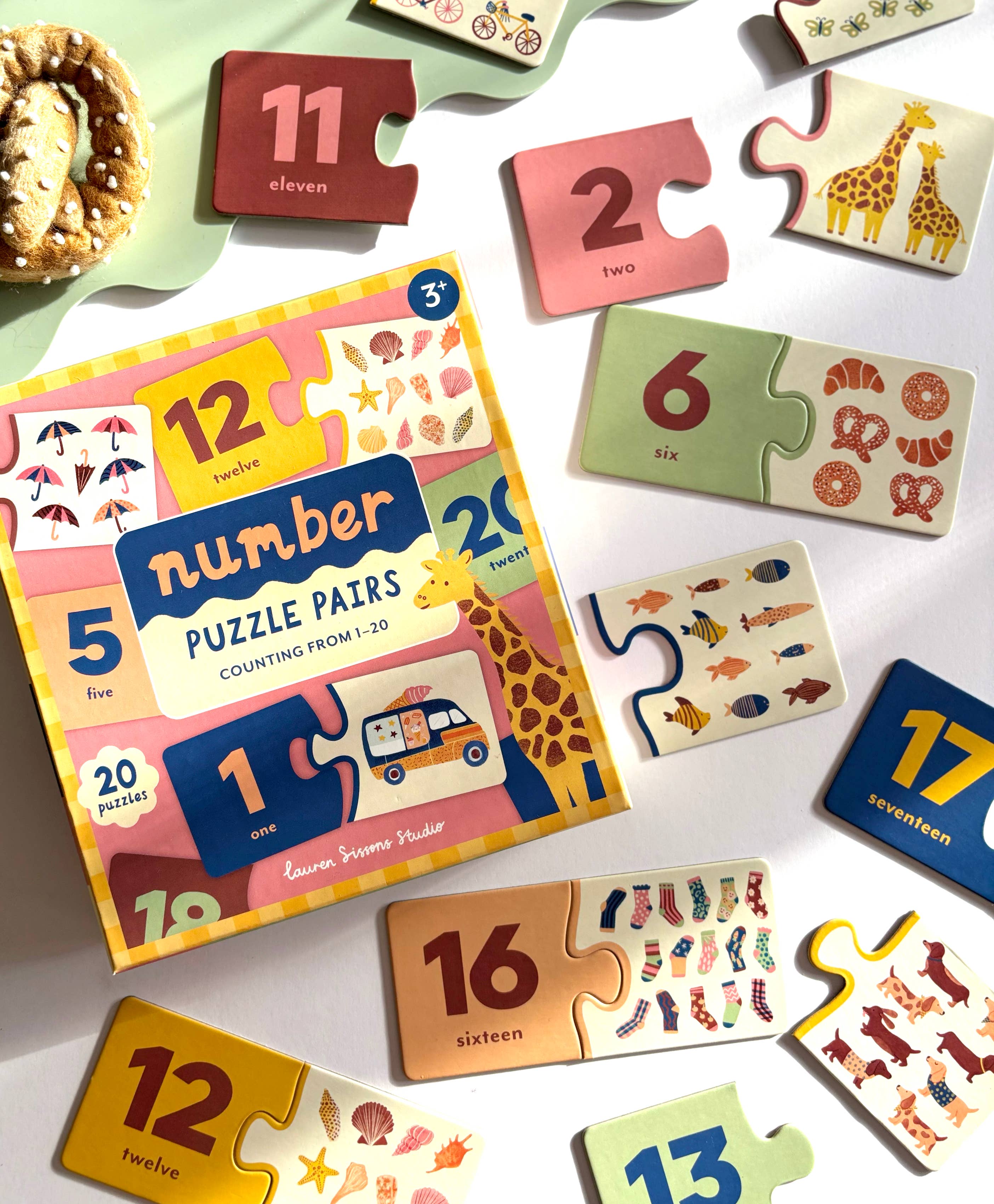 The Number Puzzle Pairs - Kids Toys Learning Game Educational by Lauren Sissons Studio includes a colorful box and matching puzzle cards with numbers, objects, and animals, helping children practice counting skills by pairing numerals with related items.