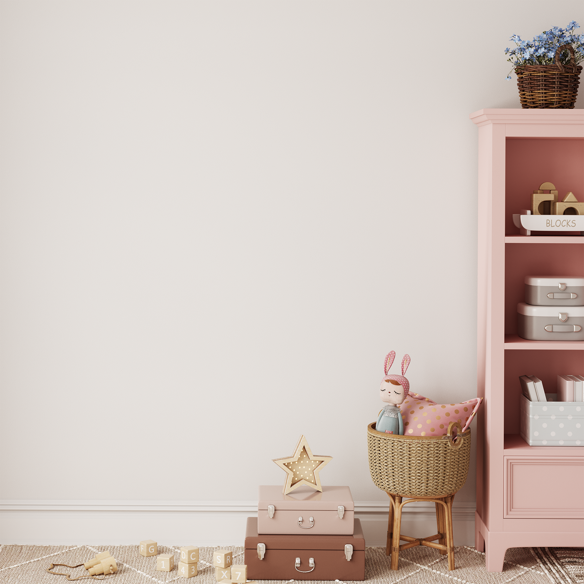 A cozy children’s room features a pink shelf, wicker basket with bunny doll, pink suitcases, wooden blocks, star decor, and a plant. The look is completed with Benji & Belle’s Striped Half Wall Bespoke Wallpaper Panels on the white wall.