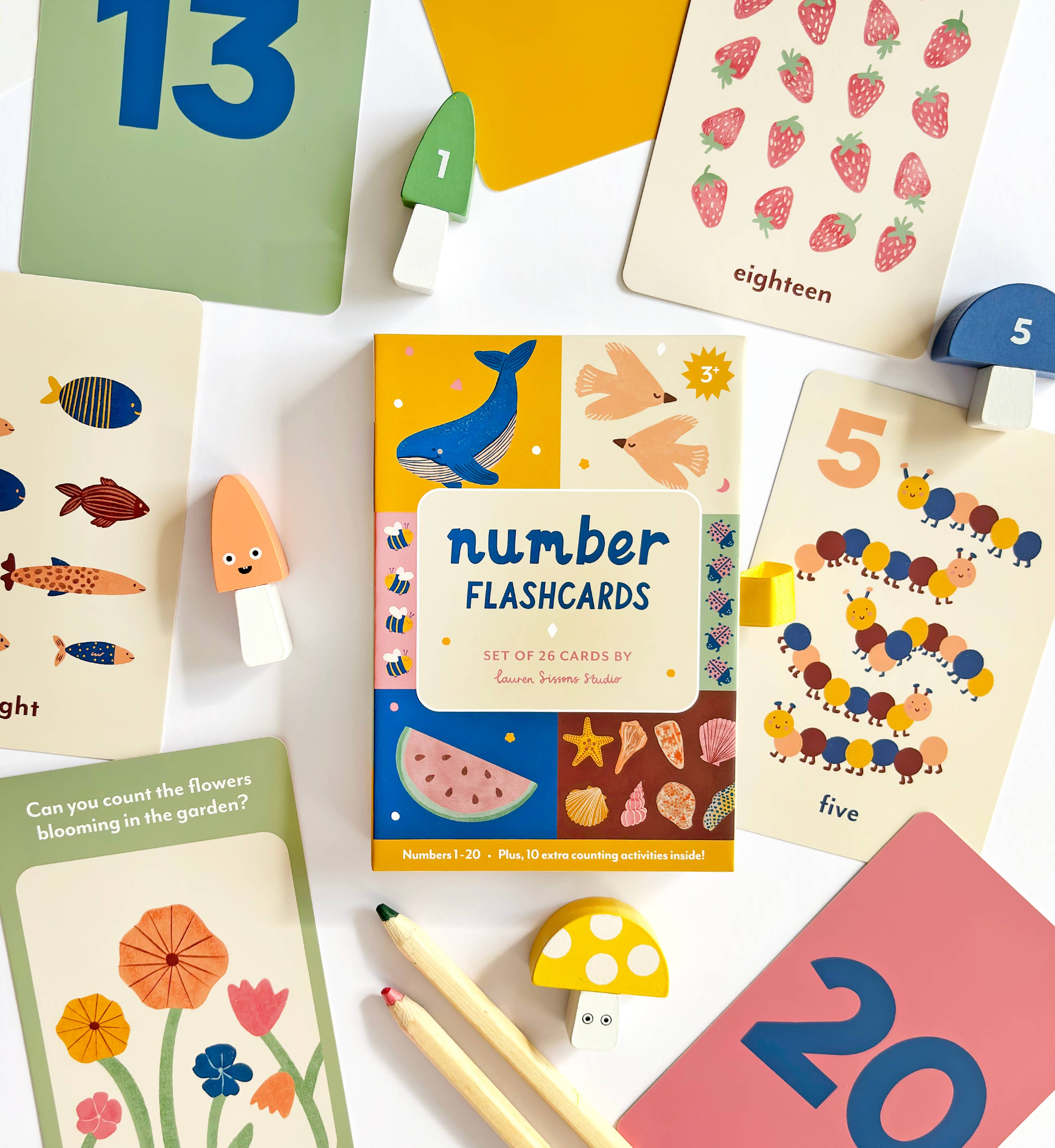Lauren Sissons Studio’s Illustrated Number Flashcards feature playful animal, plant, and number illustrations, shown with wooden mushrooms, pencils, and blocks—perfect kids’ toys for learning and education.