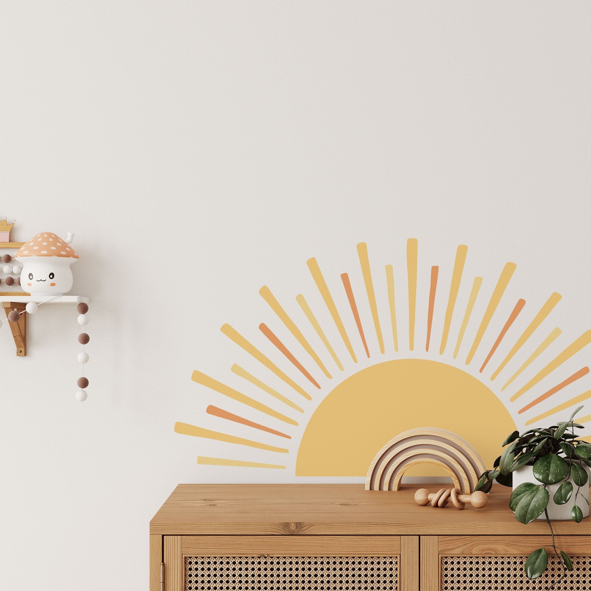 A cozy nursery room showcases a light wood cabinet with a plant, featuring My Stores Boho Sun Sticker as a backdrop. To the left, a small shelf holds a mushroom toy and beaded decor.