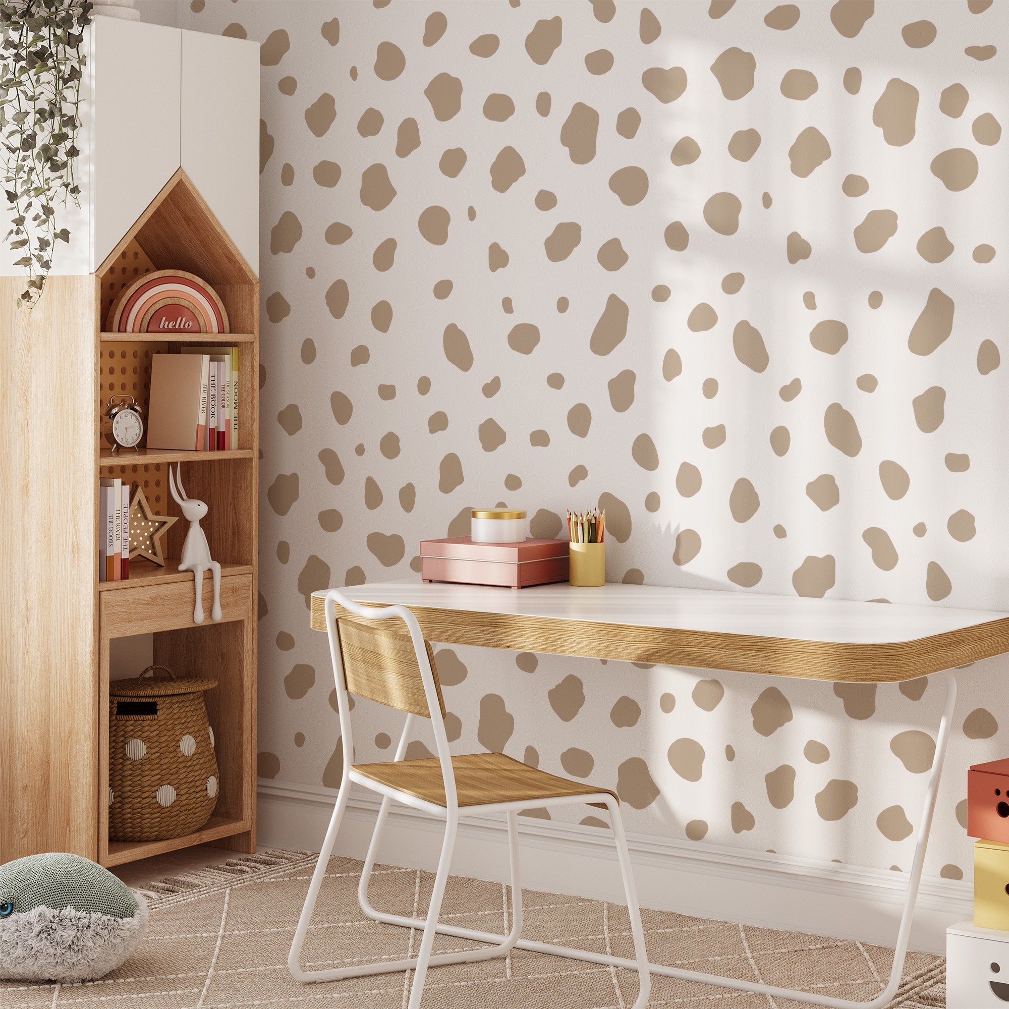 A minimalist workspace includes a white desk with wooden accents, a wooden chair, and beige polka dot wall stickers. A wooden shelf displays books and decor with a small potted plant. Large Dalmatian Spot Stickers by My Store add charm, while a plush toy rests on the floor.
