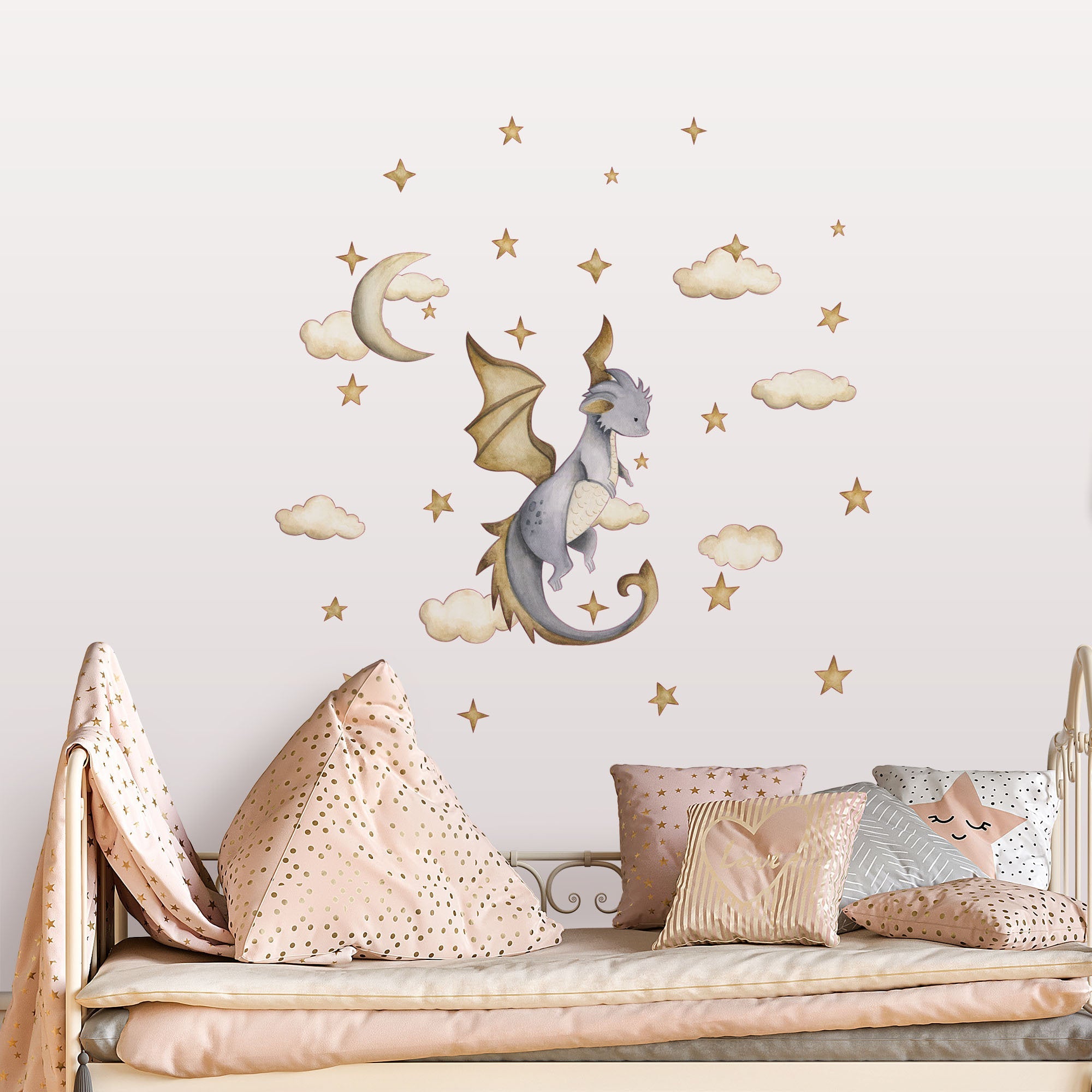 A whimsical childrens room showcases My Stores Dragon Stickers, featuring a watercolor dragon soaring through clouds, stars, and a crescent moon. The bed is adorned with polka dot and star-patterned pillows and pastel blankets, perfectly complementing the removable decals.