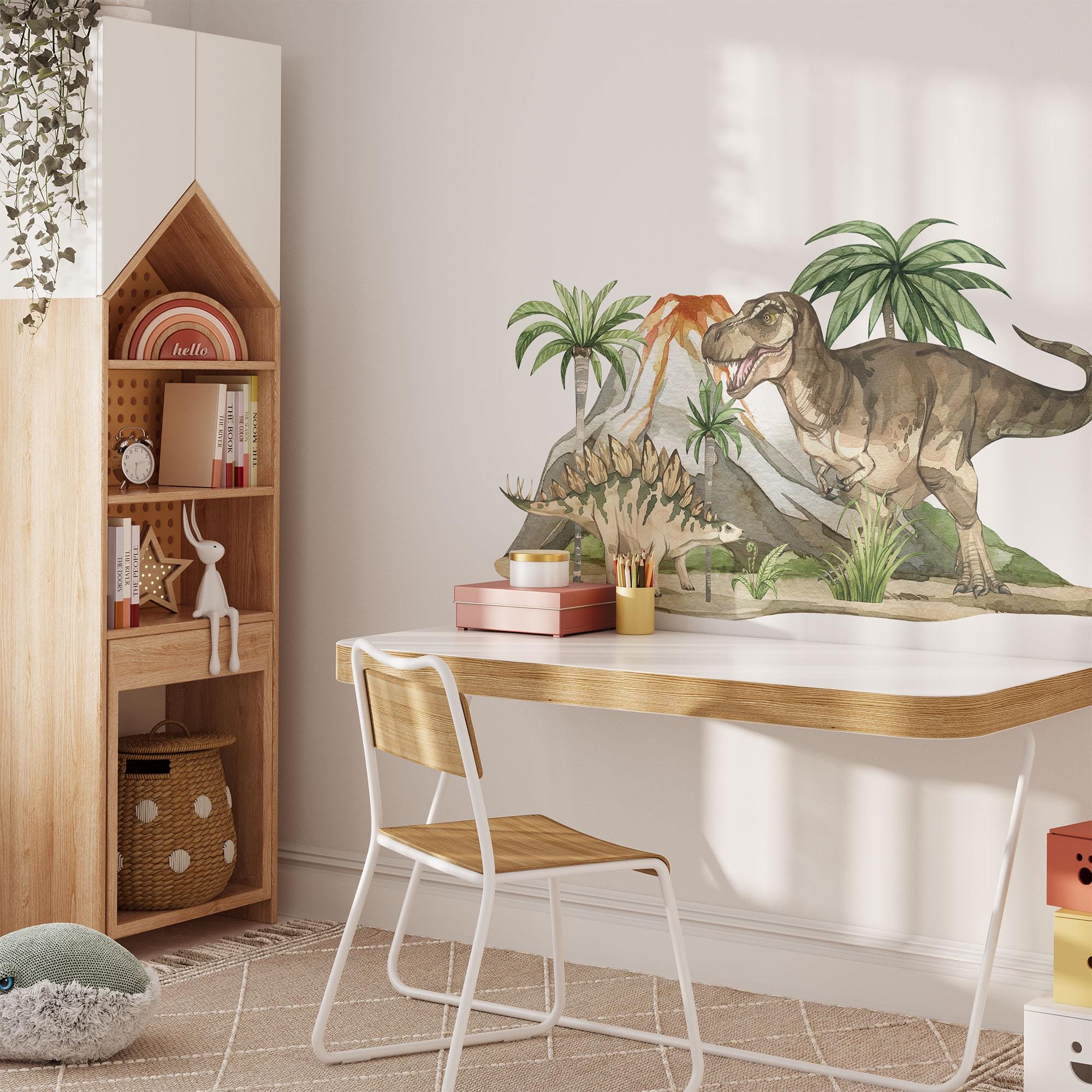 A childrens room features a modern desk and chair set against a wall adorned with My Stores Dinosaur Nursery Stickers. A house-shaped wooden shelf holds books and toys, while playful nursery decor accents the space basked in natural light.