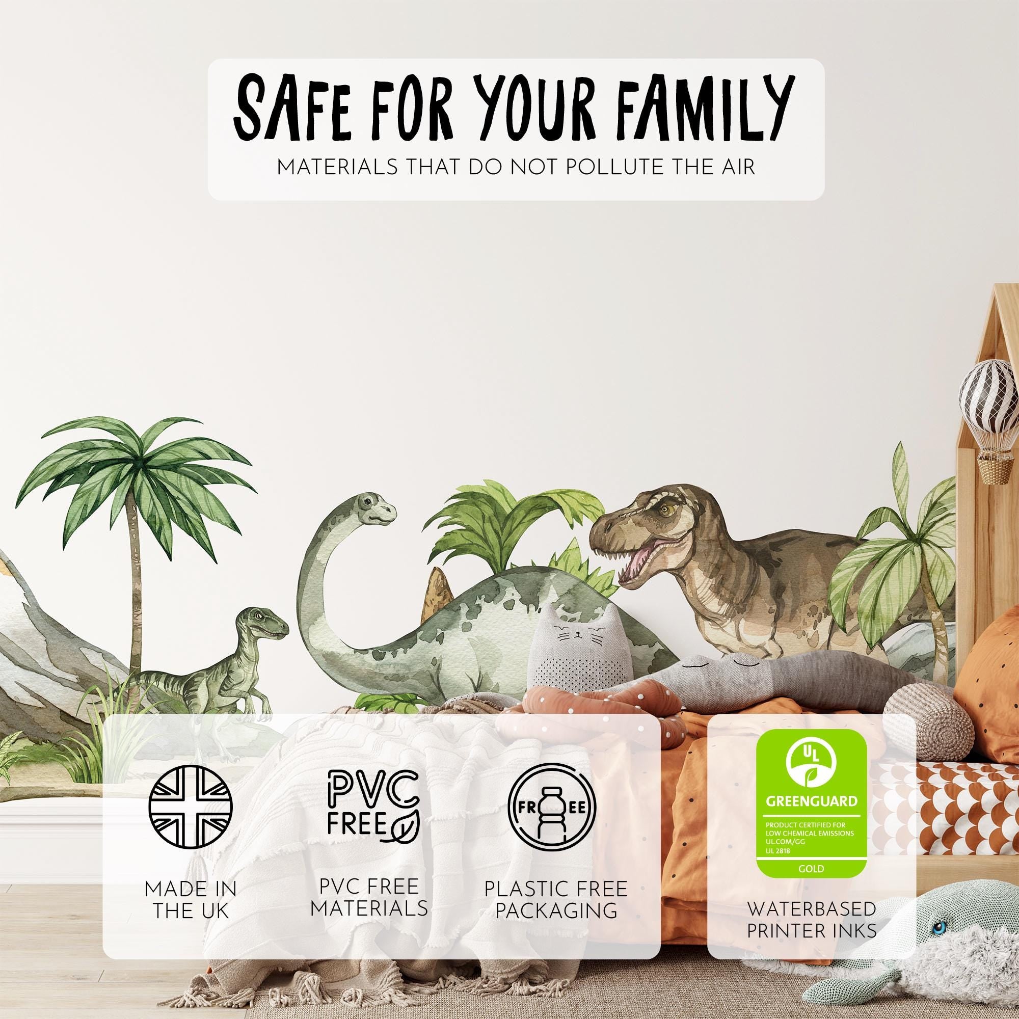 A childrens room features My Stores Dinosaur Nursery Stickers, including a T-rex and long-neck dinosaur. The cozy bed is surrounded by stuffed animals and cushions. Labels showcase eco-friendly features: PVC-free, plastic-free, and Greenguard certified.