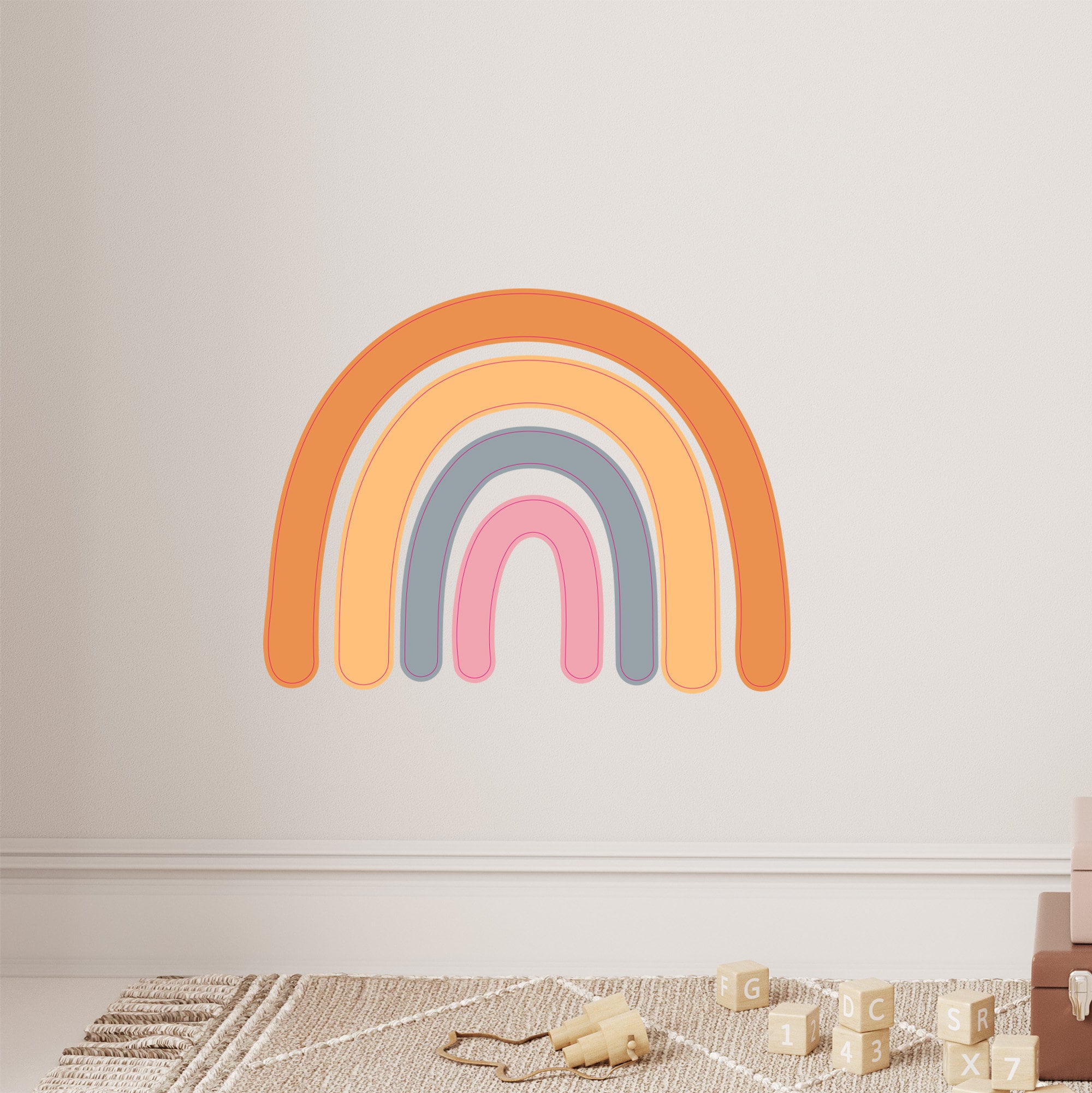 My Stores Rainbow Wall Stickers in shades of orange, pink, and blue decorate a light-colored wall. A beige rug complements the scene, while wooden alphabet and number blocks are scattered on the floor.