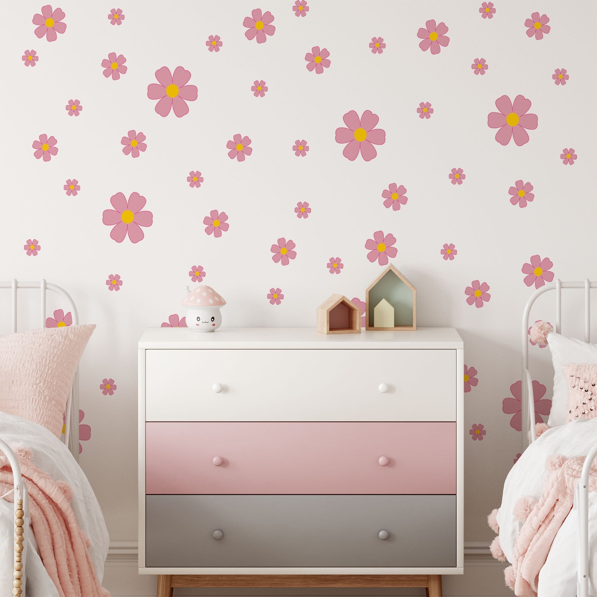 A pastel-themed children’s bedroom features a white and pink dresser, two beds with pink bedding, and a wall decorated with My Store’s Pink Daisy Floral Wall Decals—perfect nursery wall stickers for adding charm.