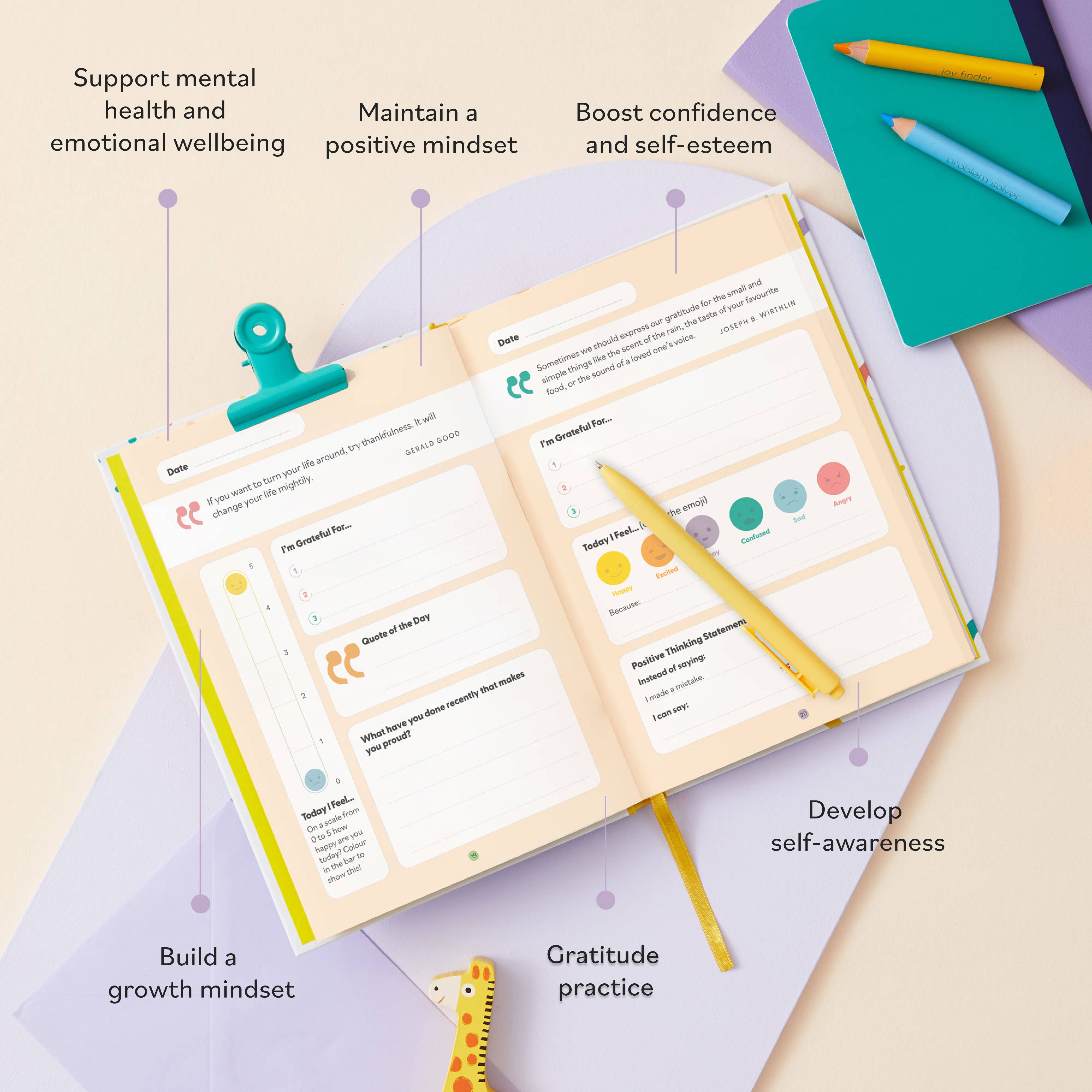 The My Mindful Me Journal by Mindful Champs lies open on a pastel desk with colorful pens and stationery, featuring daily prompts to support children's mental health, maintain positivity, boost confidence, and build self-awareness.