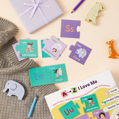 A flat lay featuring Mindful Champs’ 'A-Z I Love Me' Affirmation Puzzle, a wrapped gift, animal figurines, sweater, and pencils. This alphabet matching game builds kids’ confidence with affirmations like “I am Understanding” and “I am Strong.”.