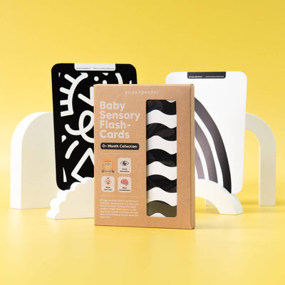 A box of Priya & Peanut Newborn Sensory Cards (0+ Months Old) | Award-Winning Baby Toy stands on a yellow background, with high contrast cards on white stands. Bold text and icons support baby's visual development.