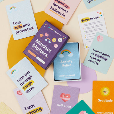 Mindful Champs’ Mindset Matters Flashcards are spread around an open box, featuring positive phrases like "I am safe and protected" to boost self-esteem and encourage a growth mindset.