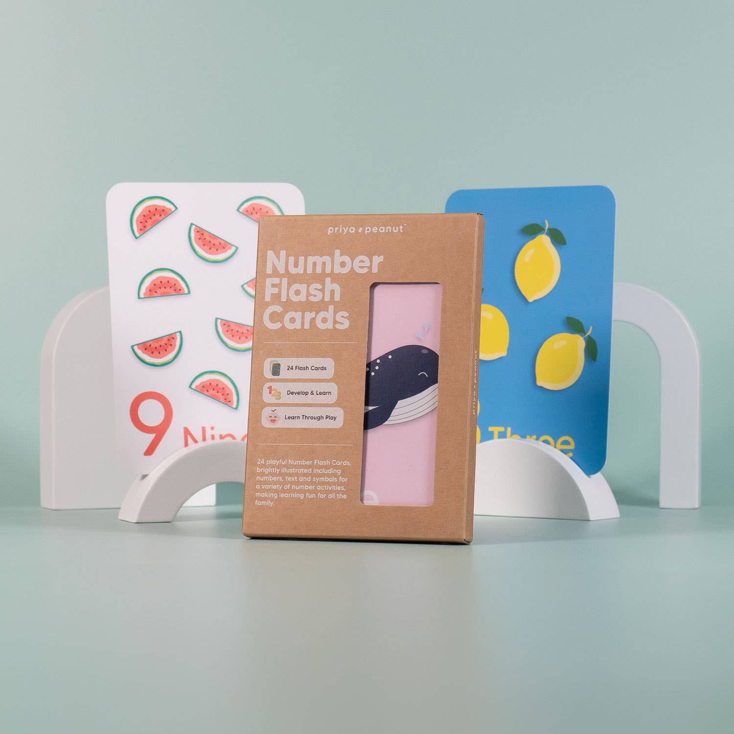 A box of Priya & Peanut's Number Flashcards | Learn To Count 0-10 Easily stands in front of two illustrated cards with watermelons and lemons, supporting number recognition and preschool learning on a pastel green background.