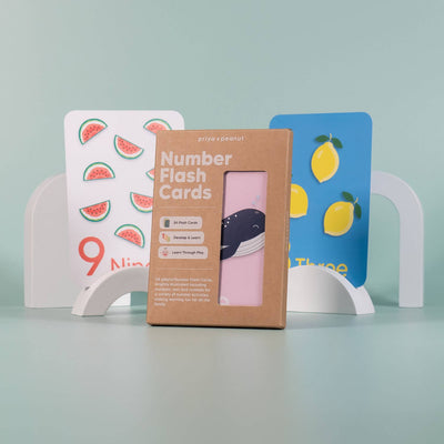 A box of Priya & Peanut's Number Flashcards | Learn To Count 0-10 Easily stands in front of two illustrated cards with watermelons and lemons, supporting number recognition and preschool learning on a pastel green background.