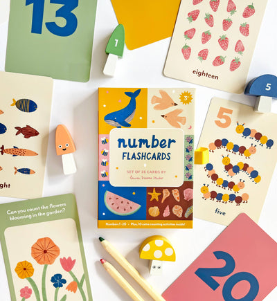 Lauren Sissons Studio’s Illustrated Number Flashcards feature playful animal, plant, and number illustrations, shown with wooden mushrooms, pencils, and blocks—perfect kids’ toys for learning and education.