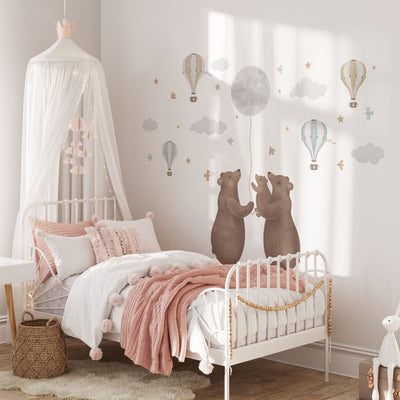 A cozy childrens bedroom features a canopy bed with pink and white bedding, whimsical Bears & Moon Stickers from My Store on the wall, and charm added by a wicker basket and small table.