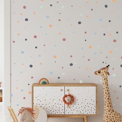 A childrens room features a white cabinet with a lion face handle, accompanied by a plush giraffe toy. The wall is decorated with My Stores Boho Polka Dots Stickers in orange, blue, and green. A stuffed horse toy peeks out, enhancing the playful decor.