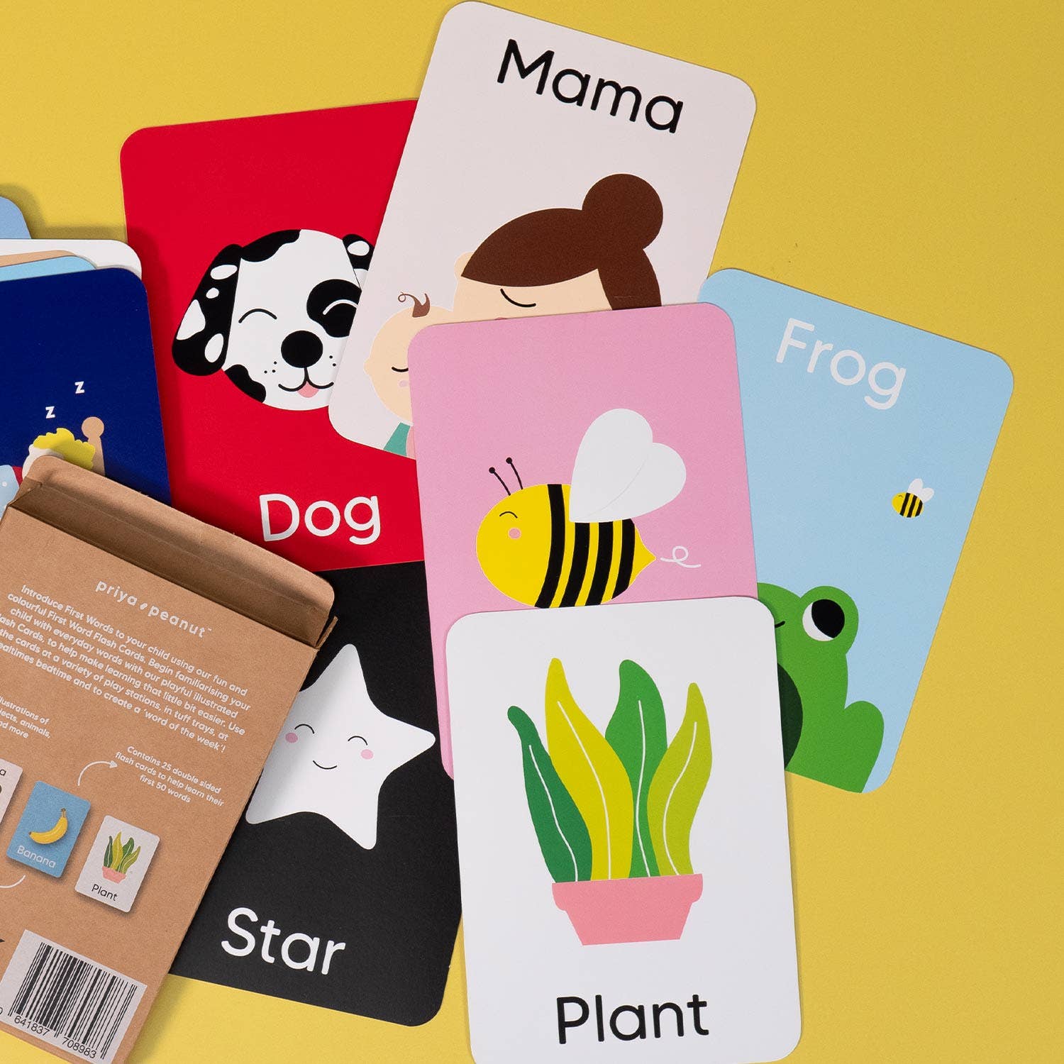 Priya & Peanut's First Word Flash Cards | 50 First Words For Toddlers are displayed on a yellow surface featuring words and drawings like dog, Mama, bee, frog, star, and plant—ideal for supporting toddler speech development. Box with instructions shown.