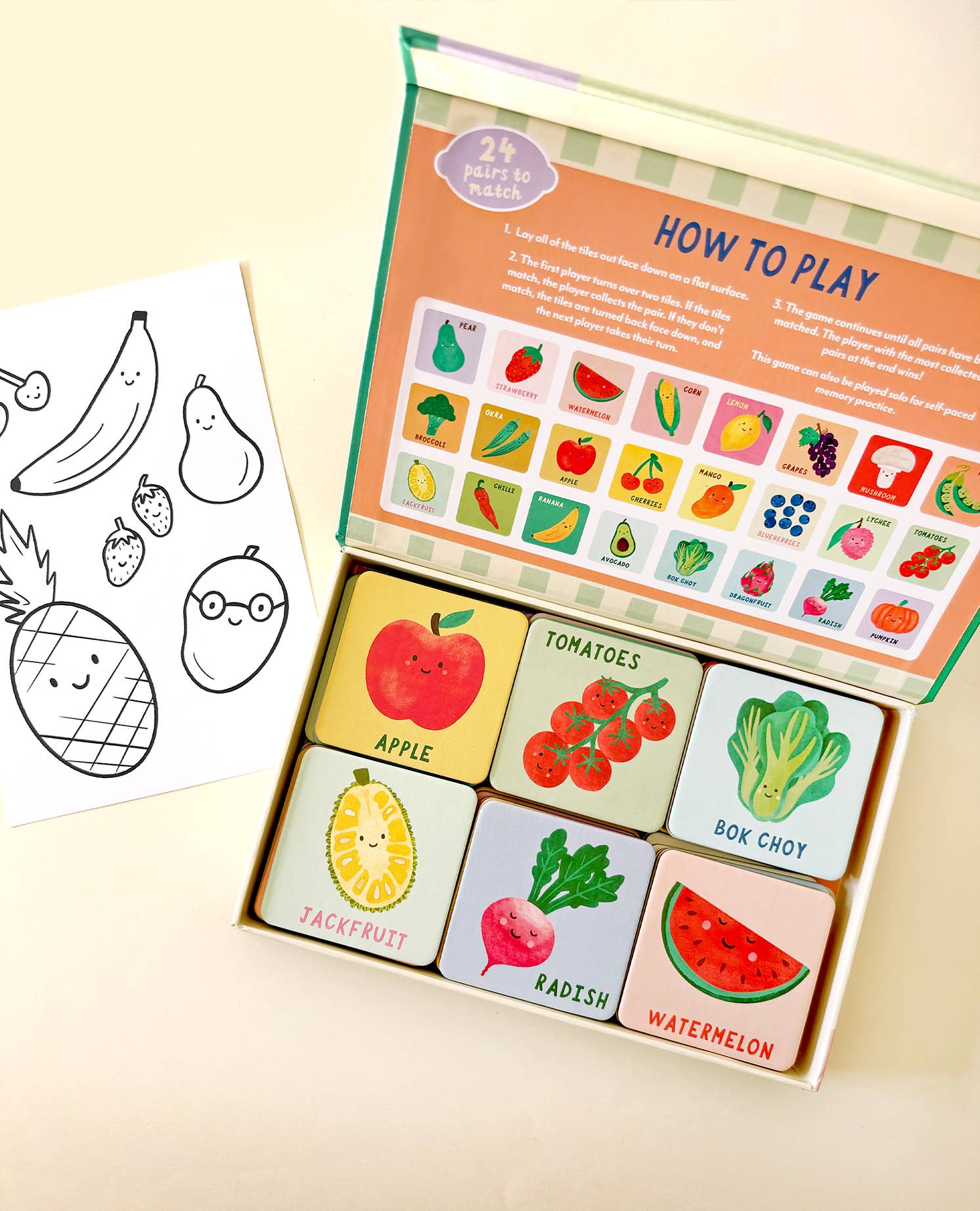 Lauren Sissons Studio's Fruit and Veg Memory & Matching Game for kids features illustrated tiles of apple, tomato, bok choy, jackfruit, radish, and watermelon. Includes instructions and a black-and-white fruit drawing—an educational gift.
