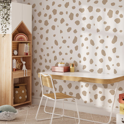 A minimalist workspace includes a white desk with wooden accents, a wooden chair, and beige polka dot wall stickers. A wooden shelf displays books and decor with a small potted plant. Large Dalmatian Spot Stickers by My Store add charm, while a plush toy rests on the floor.