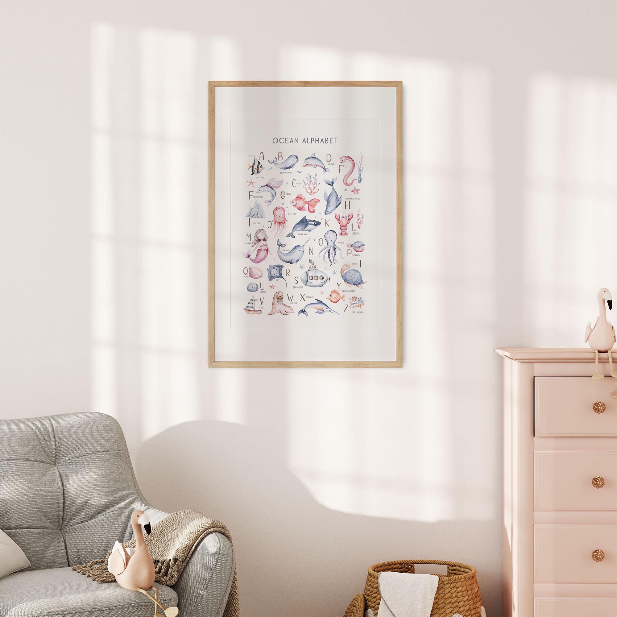 A cozy childs room with sunlight patterns on the wall features a framed Under The Sea Nursery Wall Print by My Store, offering charm and educational value with sea creatures. Above a pastel pink dresser, a gray armchair and a woven basket of toys complete the scene.