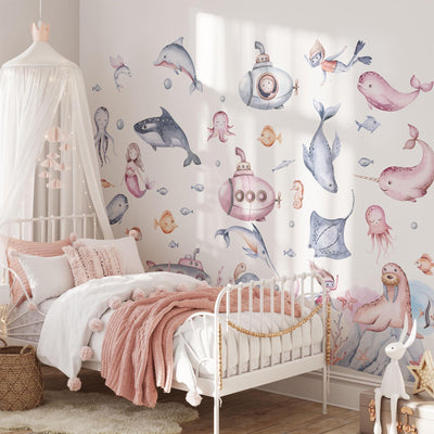 A cozy childs bedroom with a white and pink color scheme features My Stores playful Under The Sea Nursery Wall Stickers, showcasing dolphins, whales, and octopuses. A soft pink blanket and cushions adorn the white bed, with a canopy elegantly draped above.