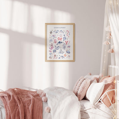 A cozy bedroom showcases a white bed with pink and white pillows, a pom-pom adorned pink throw, and fairy lights above. A framed My Store Under The Sea Nursery Wall Print adds educational charm with its marine life illustrations.