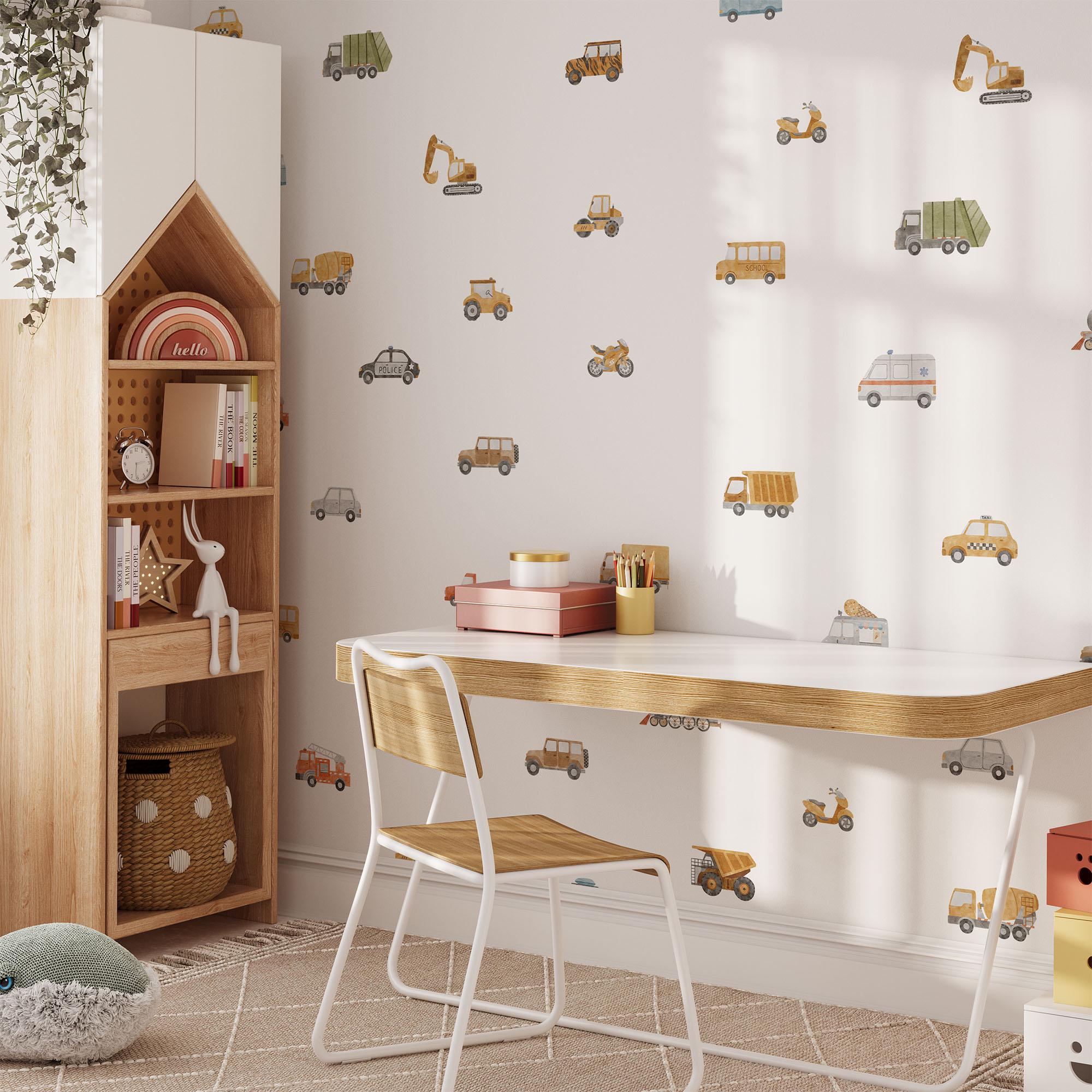 A cozy childrens room features a wooden desk and chair, My Stores Transport Vehicles Wall Stickers, and a house-shaped bookshelf. A basket, plant, and fluffy cushions enhance the playful and inviting atmosphere.