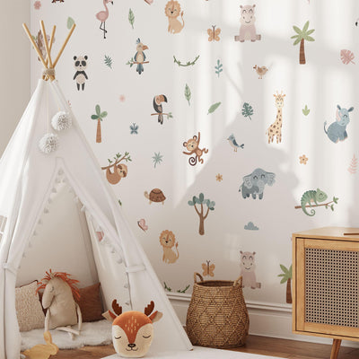A childrens room brightened by My Stores Jungle Animal Wall Stickers, featuring lions, elephants, and giraffes. A white play tent with plush toys sits on a soft rug next to a wicker basket and wooden cabinet, all bathed in natural light for a charming nursery decor.