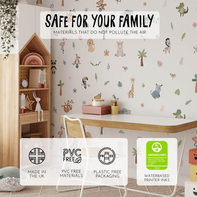 A childs room showcases nursery decor with a desk, chair, and a wooden house-shaped shelf. The wallpaper features cartoon animals and trees, complemented by My Stores Jungle Animal Wall Stickers. Eco-friendly: UK-made, Greenguard certified, PVC-free, plastic-free packaging.