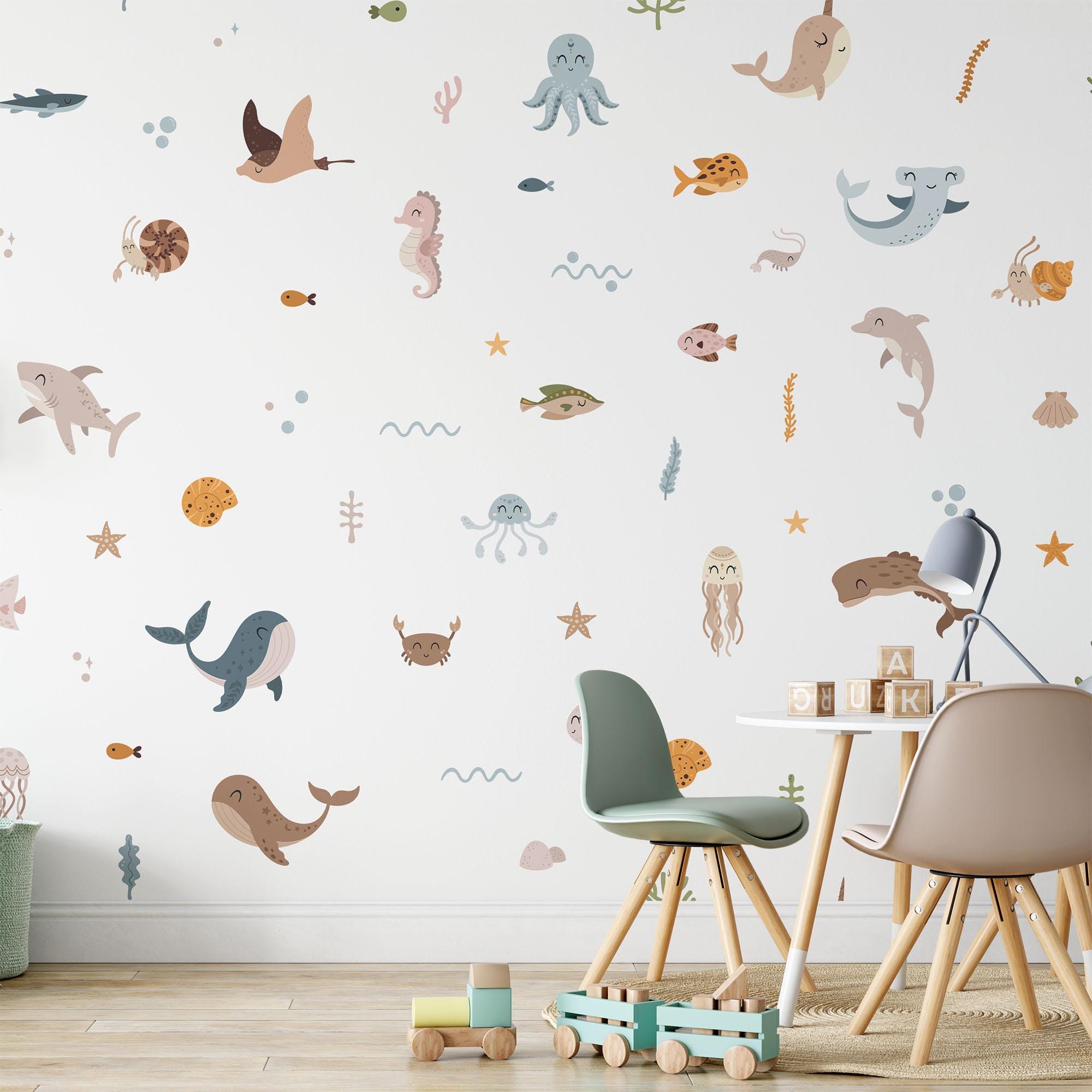 A childrens room showcases My Stores Ocean Animals Stickers, featuring sea creatures like whales, dolphins, octopuses, and turtles. The space includes pastel chairs, a small table with books, and a wooden toy truck on the floor.