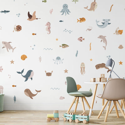 A childrens room showcases My Stores Ocean Animals Stickers, featuring sea creatures like whales, dolphins, octopuses, and turtles. The space includes pastel chairs, a small table with books, and a wooden toy truck on the floor.