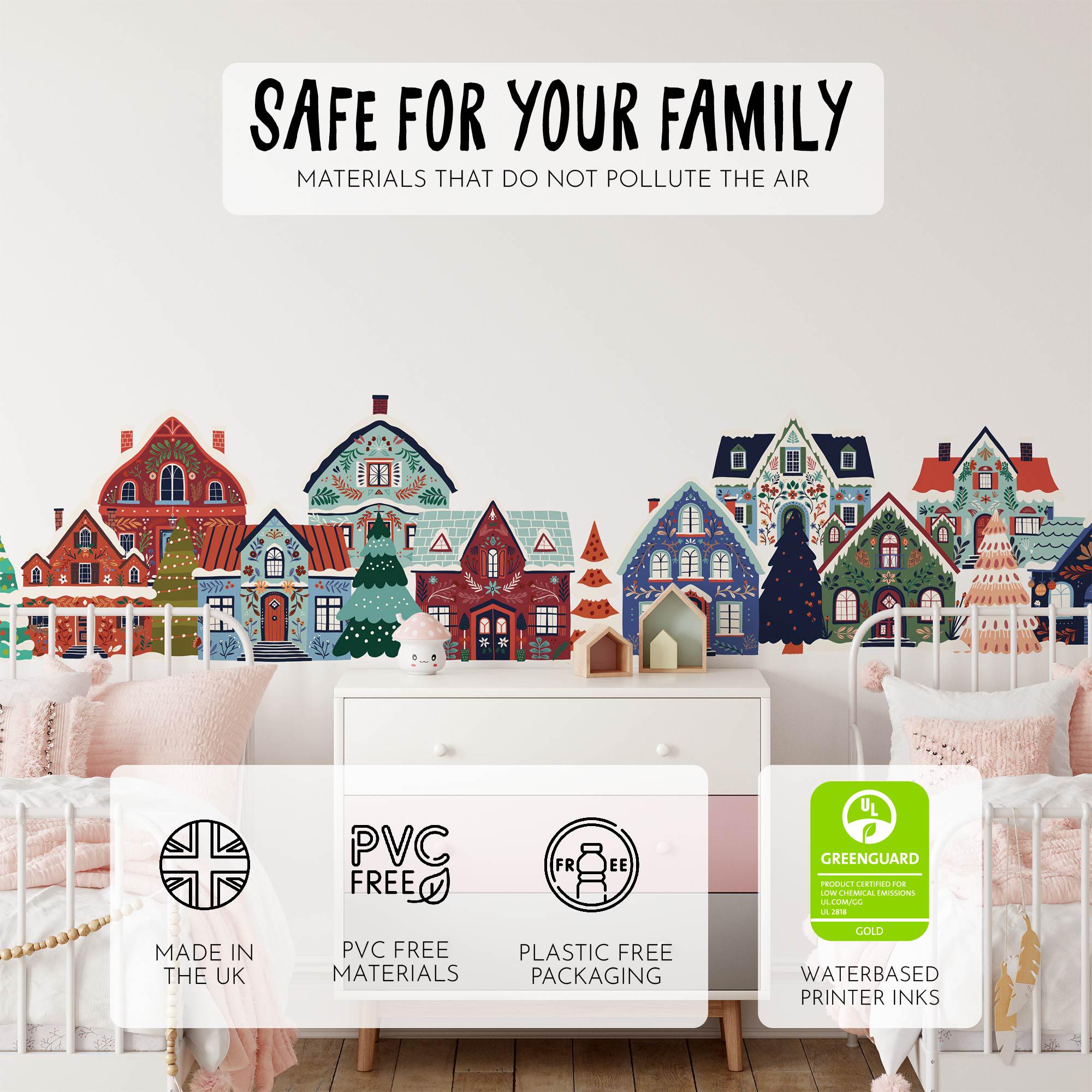 The nursery room showcases My Stores Festive Houses Wall Stickers with colorful houses and trees. Removable decals boost creativity, and Safe for your family: Materials that do not pollute the air adorns the top. Icons denote UK-made, PVC-free, plastic-free, and water-based ink features.