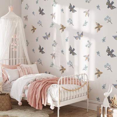 A cozy bedroom features a white metal bed with pink pillows and a fluffy blanket. Butterfly and floral Summer Mood Wall Stickers by My Store adorn the walls. A canopy hangs above, with a woven basket on the floor as sunlight streams in, creating a serene atmosphere.