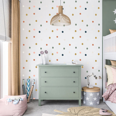 A cozy childrens bedroom features a green dresser, polka dot wallpaper, and a string of lights. My Stores Coloured Dot Stickers add charm above the partially visible bunk bed. A ceiling wicker lamp and floor soft toys complete the room while colorful decor adds a playful touch.
