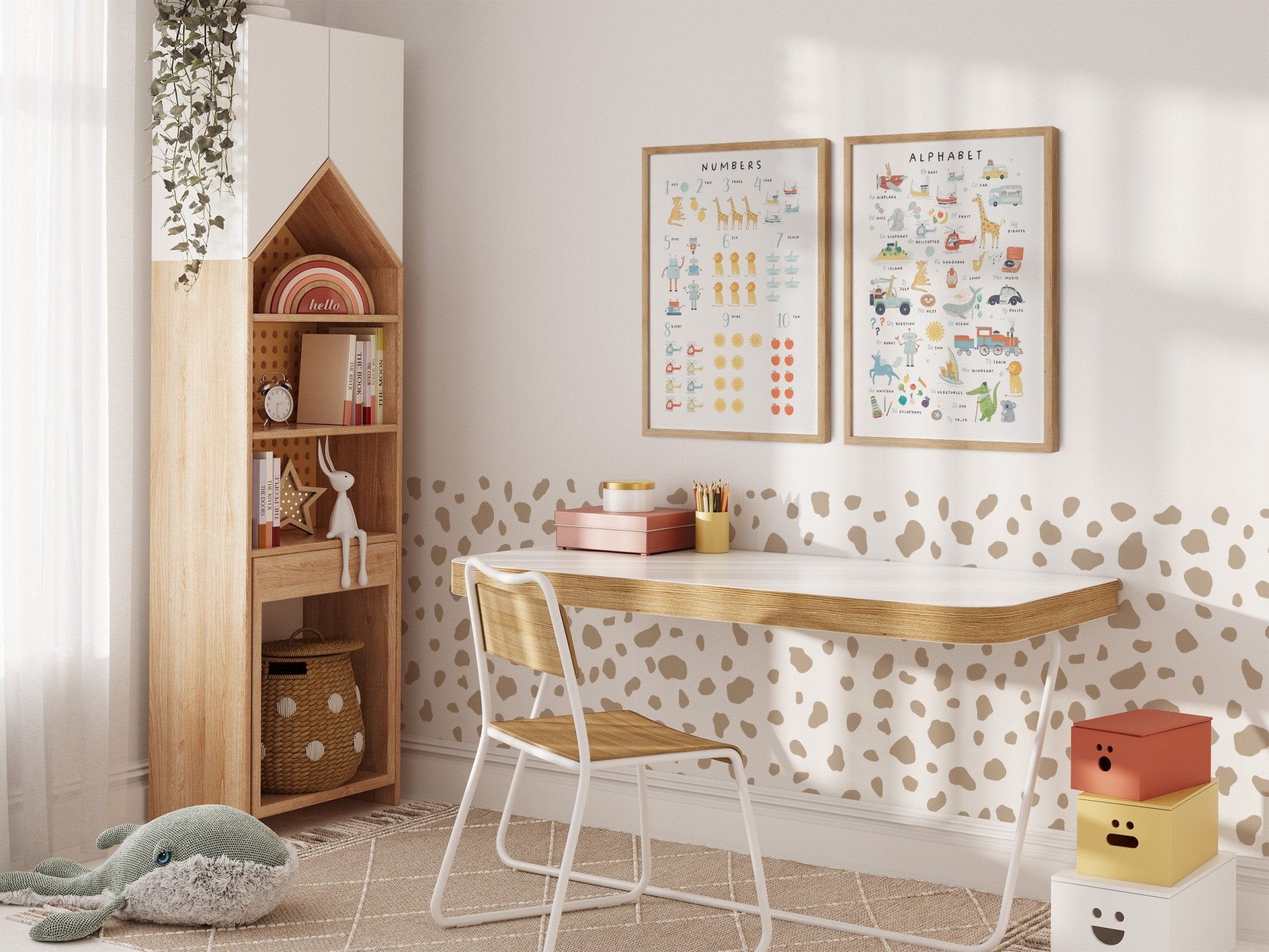 A cozy childrens room includes a wooden desk and chair, a house-shaped bookshelf, and My Stores Numbers & Alphabet Nursery Print on the wall. The space comes alive with a green plush whale toy and colorful storage boxes, adding playful elements to this enchanting environment.