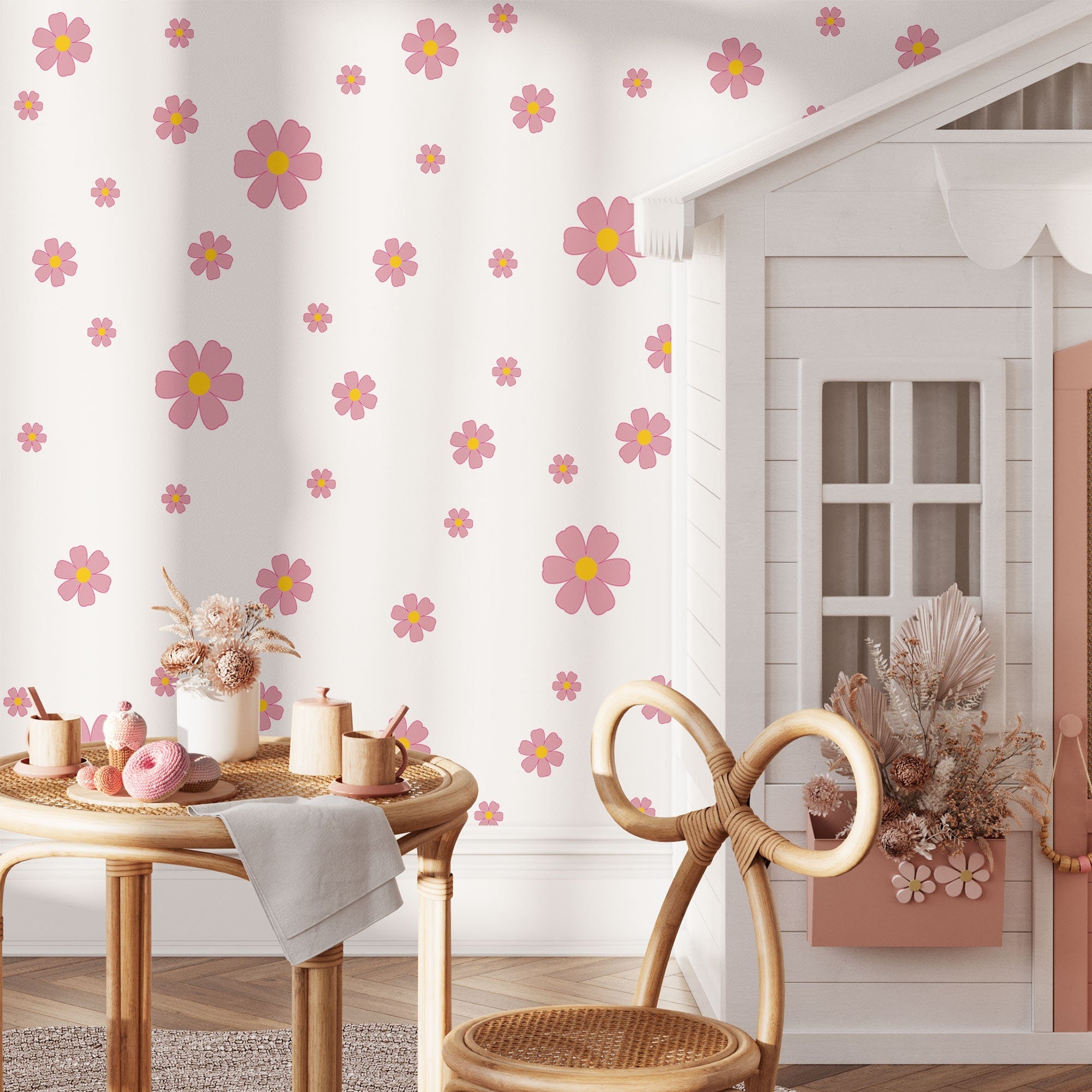 A cozy children's room features My Store Pink Daisy Floral Wall Decals, floral wallpaper with pink and yellow flowers, a playhouse, round table with chairs, and vases of dried flowers for a whimsical, inviting ambiance.