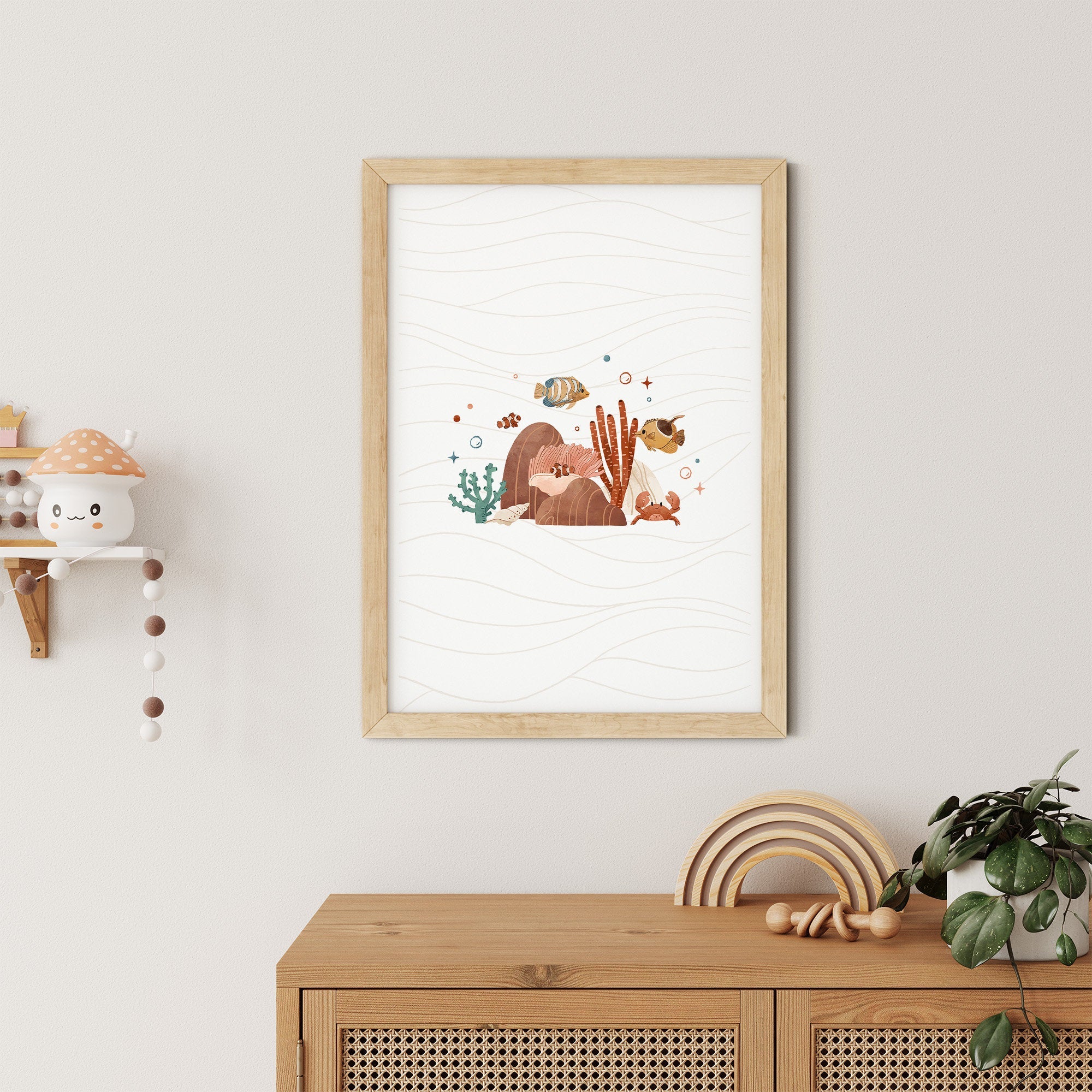 The Sea Animals Nursery Print by My Store shows fish, coral, and seaweed on a wavy background. It hangs above a wooden console table on a light-colored wall with a shelf of decor to the left and a plant on the table, ideal for an ocean-themed nursery.